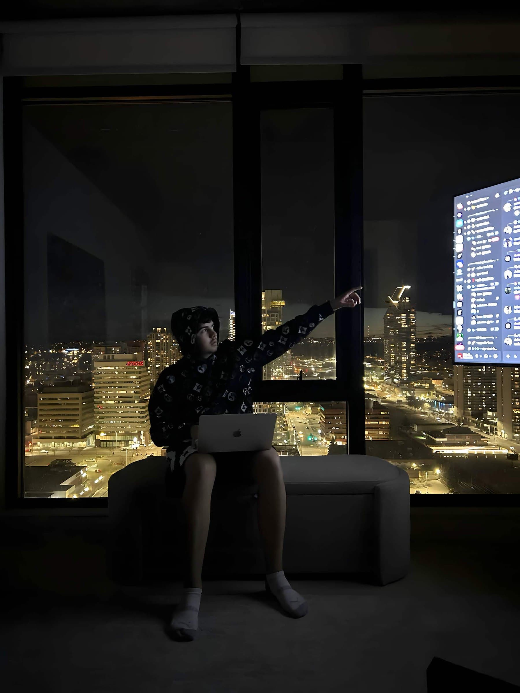 Noa Assaf silhouetted against the Calgary skyline at night